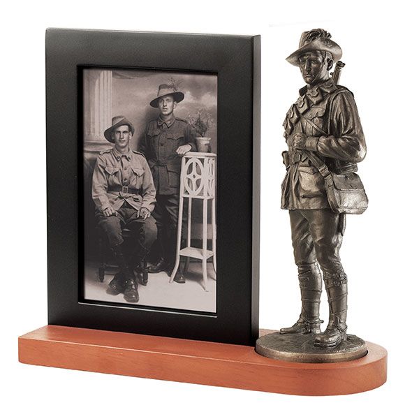Bronze statue of a soldier next to a framed black and white photo on a wooden base