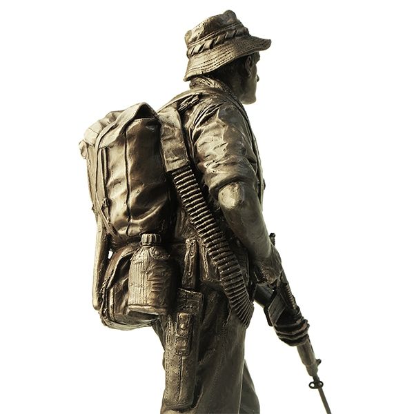 Bronze statue of a soldier with a backpack and rifle on a white background