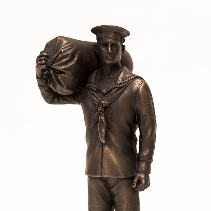 Bronze statue of a sailor carrying a bag on a white background